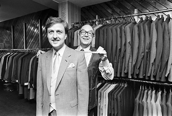 Eric Morecambe with Geouf Souster in front of a rack of suit jackets.